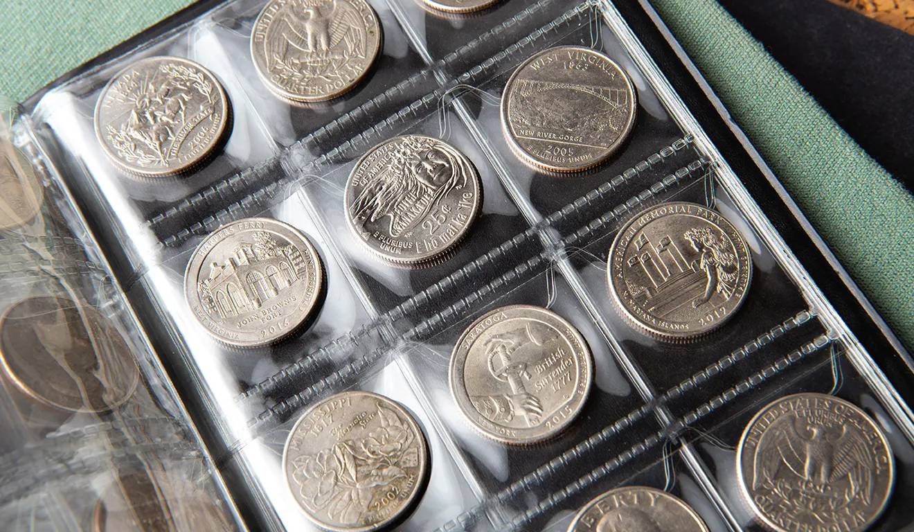 Close-up of a coin collection album with silver coins in clear plastic sleeves.