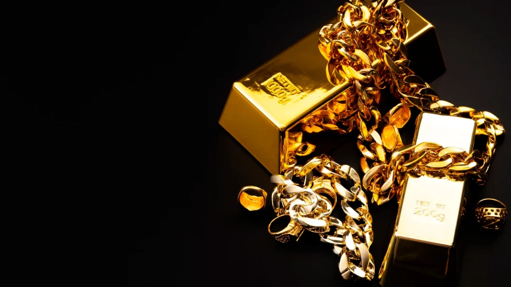 Gold bars and heavy gold chains scattered on a black surface, luxurious and glossy.